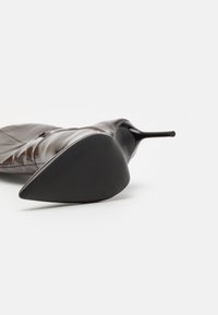 Stivaletto in pelle verniciata marrone con punta appuntita, caratterizzato da una silhouette elegante e una suola nera testurizzata.