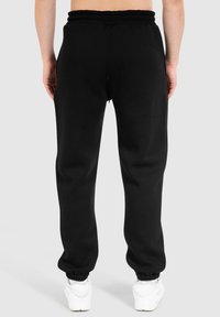 Sorte sweatpants med elastisk talje og manchetter, lavet af blødt stof. Har et lige ben design og en glat tekstur.