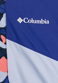 Tkanina brenda Columbia sadrži plavu površinu sivi dio i višebojni uzorak. Glatka tekstura s prošivenim rubovima.