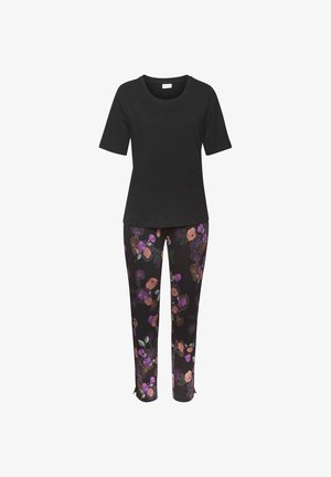 T-shirt noir à manches courtes associé à un pantalon noir orné d'un motif floral en rose, violet et vert. Le pantalon présente des fentes sur les côtés au niveau de l'ourlet.