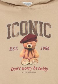 Teddy bear wearing a red beret with text "ICONIC," "EST. 1986," "You are so so cute," and "Don't worry be teddy, better days ahead."