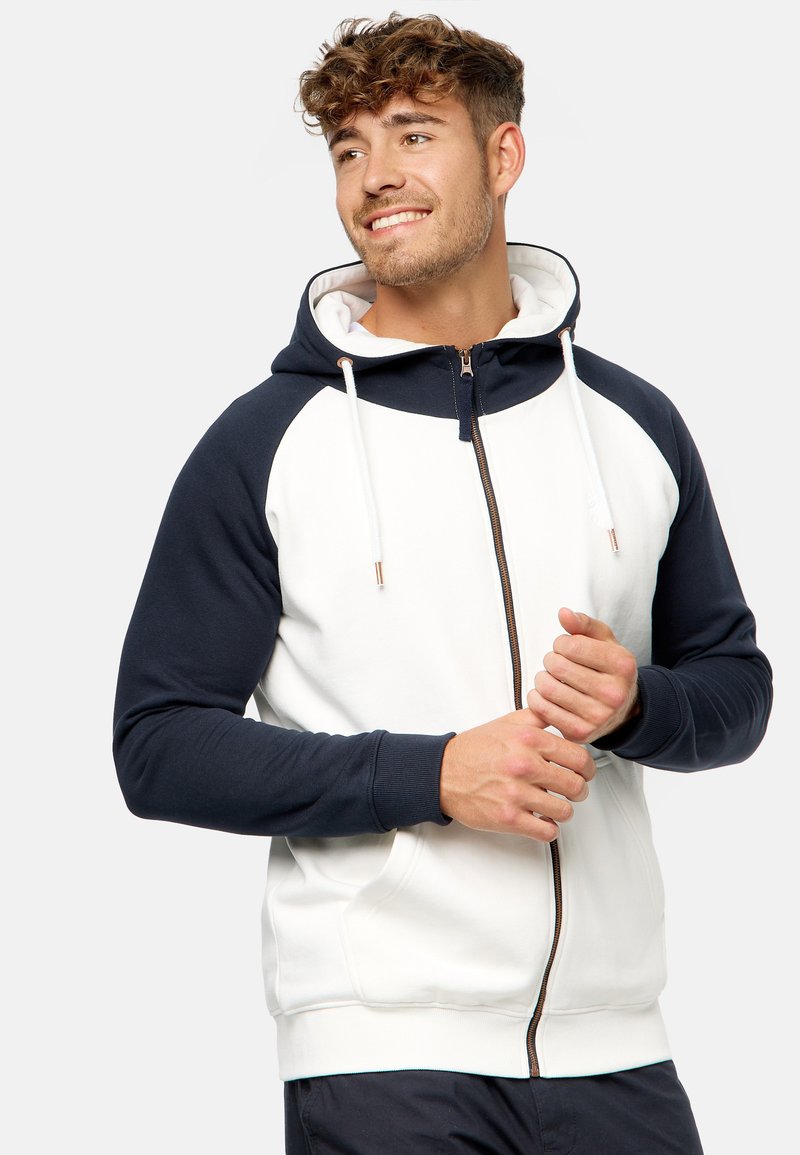 Men's zip-up hoodie in white and navy, featuring raglan sleeves, adjustable drawstrings, and front pockets. Soft fabric with ribbed cuffs.