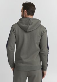 Gray hoodie with a hood, long sleeves, and navy side accents. Made of soft fabric, featuring a ribbed hem and cuffs.