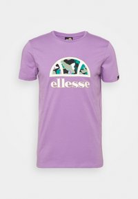 Lila bomulls t-shirt med en rund grafik med ett kamouflage-mönster i grön, blå och vit, samt "ellesse" logotypen i vitt nedanför.