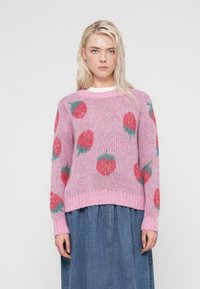 Ροζ πλεκτό πουλόβερ με άνετη εφαρμογή, στρογγυλή λαιμόκοψη και σχέδια φράουλας σε κόκκινο και πράσινο. Μανσέτες και τελείωμα με ριμπ ύφασμα προσδίδουν υφή.