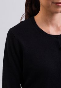 Cárdigan negro hecho de tejido suave, con un escote redondo, botones en la parte delantera y mangas largas, sin ningún tipo de patrones.