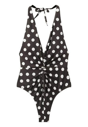 Costume intero nero con pois bianchi, scollatura a V profonda, allacciatura alla nuca a fascia e dettaglio a nodo intrecciato al centro davanti.