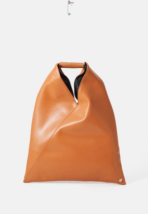 Tan leather handbag with unique triangular folds and a small wooden handle, displayed hanging against a white background.