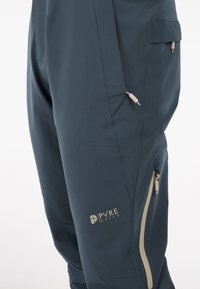 Waterbestendige cargobroek in donkerblauwe stof met beige accenten, meerdere zakken en ritsen voor een verstelbare pasvorm en functionaliteit.