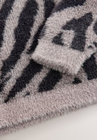 Soft, fuzzy blanket in pale pink with dark gray zebra stripes. Features a plush texture and irregular geometric patterns.