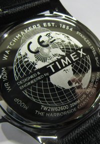 Edelstahl-Uhrenboden mit graviertem Globusdesign, Markenname "Timex" und Modellangaben; ausgestattet mit einem schwarzen Nylonarmband.