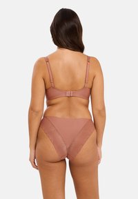 Ensemble soutien-gorge et culotte dans une couleur rose muted. Matériau doux et lisse avec des accents de motifs géométriques sur la culotte. Bretelles ajustables sur le soutien-gorge.