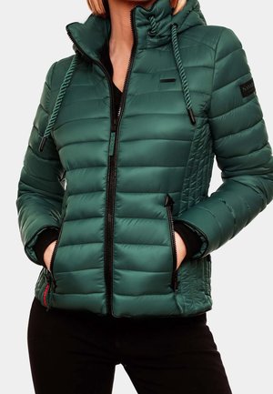 Ciemnozielona pikowana kurtka z kapturem, czarnym zamkiem błyskawicznym i kieszeniami, noszona przez osobę z rękami w kieszeniach i czarnymi spodniami.