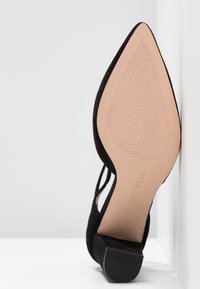 Chaussure en suède noir à bout pointu avec petit talon bloc, semelle tournée vers l'avant montrant le nom de la marque "Pier One" et la taille 37.