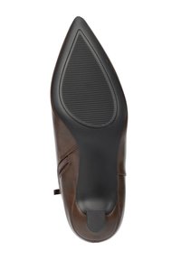 Zapato de mujer de cuero marrón con punta puntiaguda, suela de goma negra texturizada y pequeño cierre lateral, visto desde abajo.