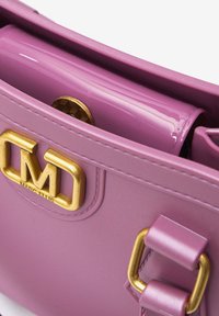 Paarse gepatineerde leren handtas met gouden hardware, voorzien van een opvallend logo en textuurdetails op de sluiting.