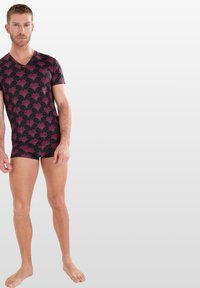 Haut noir à manches courtes avec un motif de vagues roses, associé à un short sombre assorti. Tissu doux avec une coupe ajustée. Style minimaliste.