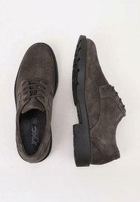 Un par de zapatos de vestir de ante gris oscuro con cordones y suelas de goma negra, vistos desde arriba y de lado sobre un fondo claro.