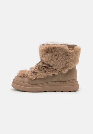 Bottes en fourrure marron avec une surface douce et texturée, un col rembourré et une semelle en caoutchouc robuste et nervurée. Dotées de lacets et d'accents décoratifs.