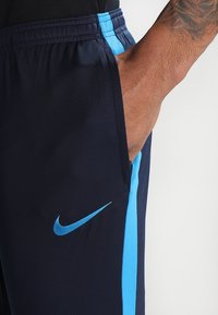 Granatowe szorty sportowe z jasnoniebieskim paskiem po boku i logiem Nike. Wykonane z oddychającego materiału, z elastycznym pasem i boczną kieszenią.