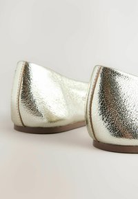 Metallisch silberne Ballerinas mit strukturierten Oberflächen, abgerundeter Spitze und niedrigem Absatz. Verfügt über sanfte Kanten und einen subtilen Kontrast zwischen den Materialien.