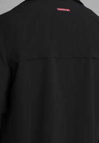 Svart kortärmad skjorta med en röd SIKSILK-logotyp på baksidan, tillverkad av ett mjukt, lätt material med en lös, avslappnad passform.