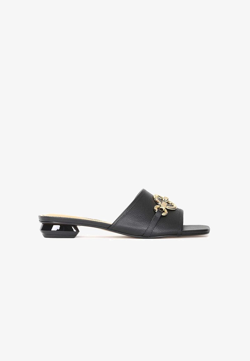 Sandale noire à bout ouvert type mule avec un talon géométrique bas et une boucle décorative dorée sur une large bride en cuir.