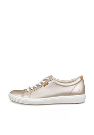 Baskets basses en cuir beige avec lacets blancs, semelle blanche et petite étiquette logo beige sur le côté sur fond blanc.