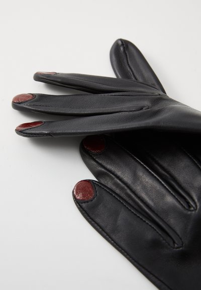 Gants en cuir noir avec des accents rouge au bout des doigts. Texture lisse, design ajusté et détails de couture soignés.