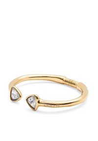 Brazalete de puño chapado en oro que presenta dos piedras preciosas transparentes en forma de triángulo en cada extremo, textura suave y un diseño flexible.