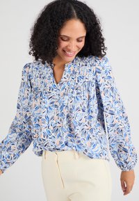 Lichte, lange–mouwen blouse in een blauw, roze en wit bloemenpatroon; geplooide details bij de halslijn; knoopsluiting.