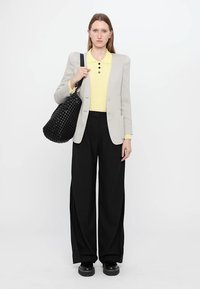 Light grey blazer, yellow polo shirt, black wide-leg trousers, black woven bag, and chunky black shoes. Simple design, smooth fabric texture.
