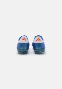 Scarpe da calcio blu con effetto sfumatura, accentuazione bianca sul tallone e logo con tre strisce rosse. Progettate per prestazioni e stabilità sul campo.