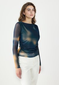Maglia a maniche lunghe blu scuro con motivo astratto arancione e crema, realizzata in un materiale liscio ed elastico con dettaglio arricciato sul lato.