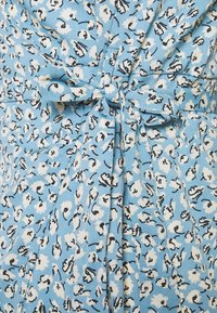 Modrý látkový materiál s bílým květinovým vzorem, doplněný černými akcenty. Obsahuje detaily se zavázaným pasem a sklady pro vyšší texturu.