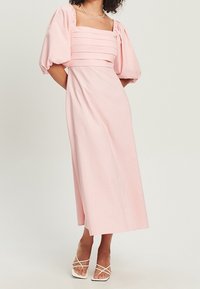 Vaaleanpunainen midi-mekko puffihihnoilla ja neliönmallisella pääntiellä, jossa on vaakasuoria poimuja bodice-osassa ja sileä, virtaava rakenne.