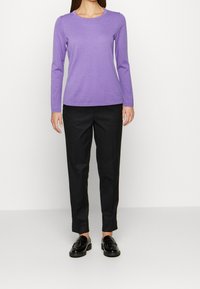 Long-sleeve purple top with a round neckline, paired with black tailored pants and black loafers. Smooth texture and fitted design.