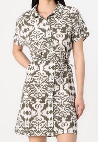 Robe à manches courtes en vert et blanc, arborant un motif abstrait, un col, une fermeture à boutons sur le devant et une taille accentuée par un lien.