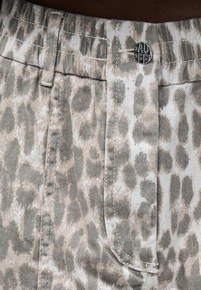 Κοντινό πλάνο σε μπεζ και γκρι παντελόνια με λεοπάρ σχέδιο, μεταλλικό κουμπί και ορατές ραφές γύρω από τη μέση και την θηλιά της ζώνης.