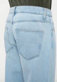 Ljust blå denimjeans med hög midja, som har två bakfickor, en slät yta och ton-i-ton sömnadsdetaljer.
