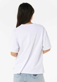 Hvid bomulds t-shirt med korte ærmer, afslappet pasform, rund halsudskæring og synlige sømme. Båret med lyseblå denimshorts.