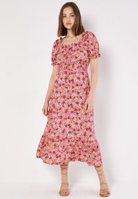 Blumen-Midi-Kleid in Pink, mit gerafftem Oberteil, Puffärmeln und einem fließenden Saum. Das Material wirkt leicht und hat ein lebhaftes Muster.