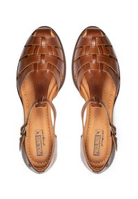 Sandalias de cuero marrón con diseño trenzado, punta abierta, correa al tobillo con hebilla y plantilla acolchada. Presenta una textura suave y costuras detalladas.