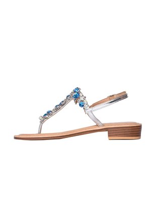 Sandalo piatto argento con tacco basso in legno e decorazioni di pietre preziose blu e trasparenti sulle fasce.