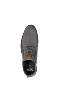 Grijze suède schoen met een gestructureerd oppervlak, ronde neus, marineblauwe veters en een bruin lederen accent op de hiel. Zwarte binnenvoering en zichtbaar logo.