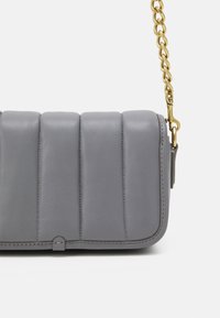 Borsa a tracolla in pelle grigia imbottita con cuciture verticali e tracolla in catena dorata su sfondo bianco.