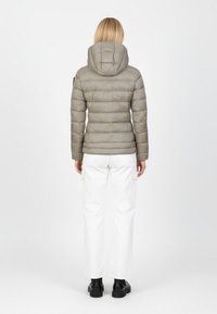 Steppjacke in Hellgrau mit Kapuze, gesteppter Textur und einer taillierten Silhouette. Kombiniert mit weißen Cargohosen und schwarzen Stiefeletten.