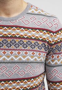 Pullover grigio lavorato a maglia con motivi geometrici in rosso, giallo, verde e bianco. Collo rotondo, tessuto testurizzato, larghezze di linea variabili.