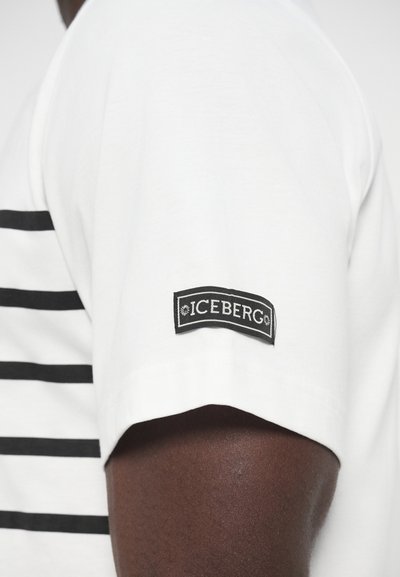 Λευκό μπλουζάκι με κοντά μανίκια και μαύρες οριζόντιες ρίγες, με μαύρο λογότυπο "ICEBERG" στη μανσέτα. Απαλό βαμβακερό υλικό.