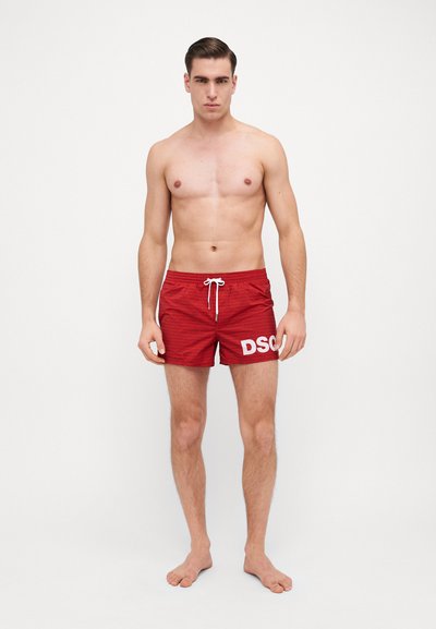 Røde badshorts med et teksturert mønster, hvit "DSC" logo på venstre ben, elastisk midje med snor, og kort lengde.